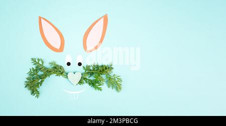 Osterhäschen-Gesicht mit herzförmiger Nase und Schnurrbart aus Karottenblättern, Weihnachtsgrußkarte, Frühlingssaison Stockfoto
