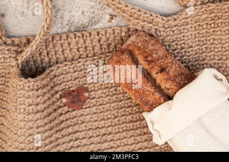 Konzept. Natürlich, umweltfreundlich. Brot liegt auf einem handgemachten Hanfkäufer. Holztisch als Hintergrund. Stockfoto