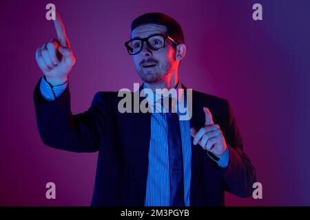 Neue Idee. Porträt eines jungen weißhäutigen Geschäftsmanns in Business-Anzug und Brille mit einem durchdachten Gesichtsausdruck auf lila Hintergrund. Stockfoto