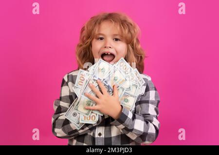 Kind mit vielen Dollar-Banknoten isoliert auf rosa rotem Studiohintergrund. Stockfoto