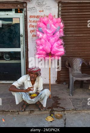 Rajasthani-Mann, der auf der Straße isst und rosa Süßigkeiten verkauft, Rajasthan, Pushkar, Indien Stockfoto