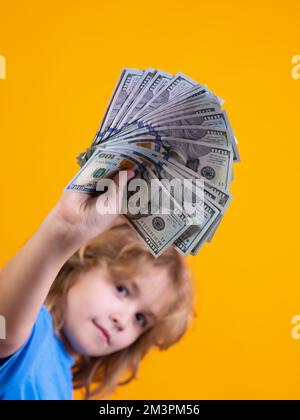 Das Kind hat viele hundert Dollar isoliert auf gelbem Hintergrund. Stockfoto