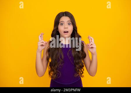 Wütendes Teenager-Mädchen, aufgebracht und unglückliche negative Emotionen. Glückliches Teenager-Mädchen kreuzt die Daumen, erwartet gute Nachrichten, isolierter gelber Hintergrund. Stockfoto