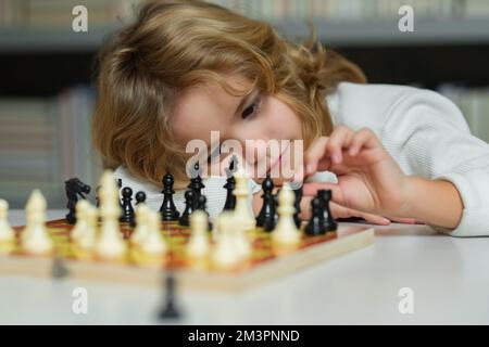 Schachschule. Kinder denken oder planen über Schachspiel, Kinder Bildungskonzept. Intelligente, kluge und clevere Schulkinder. Kinder Frühentwicklung. Kleiner Junge Stockfoto