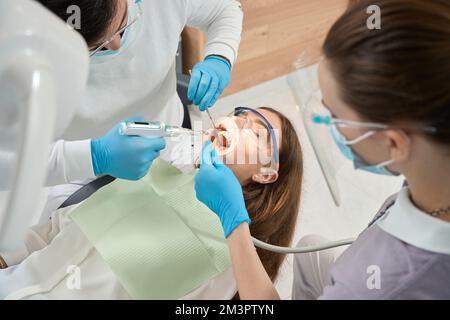Zahnärztliches Personal bei der Vorbereitung der Patientin für die Zahnbehandlung Stockfoto