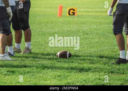 Die amerikanischen Fußballspieler mit einem Ball auf dem grünen Feld. Stockfoto