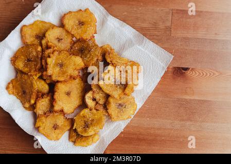 Gebratene Scheiben reifer Mehlbananen-Chips , traditionelle und beliebte Snacks und Beilagen in Mittel- und Südamerika, fotografiert über Kopf auf Leiste Stockfoto