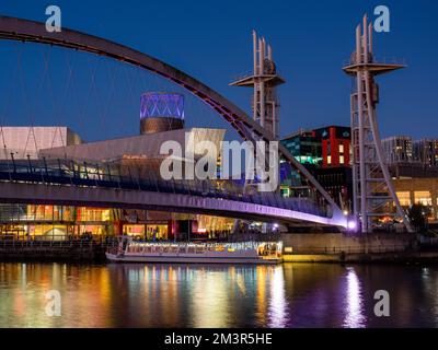 Salford Quays Manchester UK 2022 Nacht Aussicht auf Salford Quays mit Vergnügungsboot auf dem Fluss unter der Brücke neben dem Lowery Theater Stockfoto