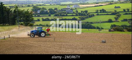 County Cork, Irland, 20. August 2022. Ein Traktor sät ein gepflügtes Feld in einem Sommer in Irland. Landwirtschaftliche Arbeiten auf einem irischen Hof, Landschaftsbau Stockfoto