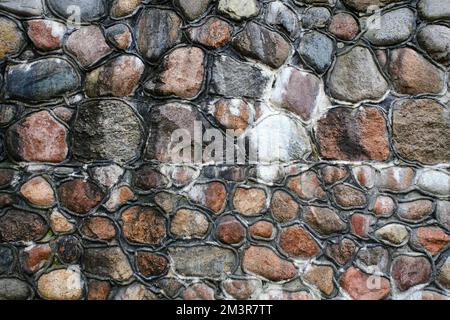 Hintergrund ist eine alte Steinwand aus Kopfsteinpflaster Stockfoto