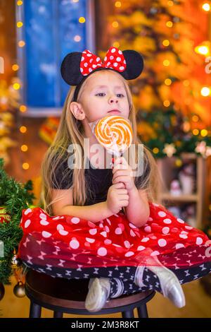 Ein Mädchen im Silvesterkostüm an einem Tisch mit Mandarinen Stockfoto