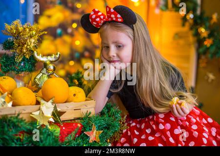 Ein Mädchen im Silvesterkostüm an einem Tisch mit Mandarinen Stockfoto