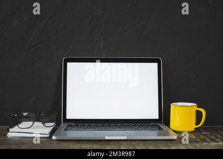 Laptop Brille Gelb Kaffeetasse Tagebuchtisch mit schwarz strukturierter Wand, Auflösung und hochwertigem, wunderschönem Foto Stockfoto