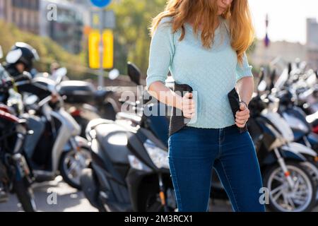 Eine rothaarige Frau legt einen Gürtel an, um ein Motorrad zu fahren Stockfoto