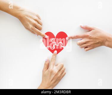 Die Hände berühren Puzzle-Herzstücke. Auflösung und hochwertige Fotos Stockfoto