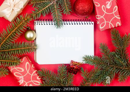 Hintergrund für Weihnachten und Neujahr. Weihnachtsgrußkarte. Weihnachtsgeschenke Kartons verpackt in Kunsthandwerk und Pinienzweige auf rotem Hintergrund Top V Stockfoto