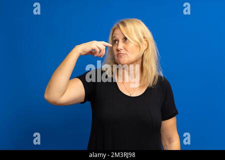 Foto einer verrückten, erstaunten Frau, die mit dem Zeigefinger auf sich zeigt, beeindruckt, Nachrichten auswählt, isoliert vor blau getöntem Hintergrund. Stockfoto