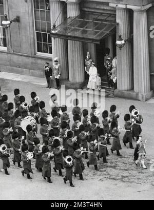Eine Szene auf dem Vorplatz des Buckingham Palace, in der Prinz Charles (König Karl III.) neben seiner Mutter, Königin Elizabeth II., zu sehen ist, wie sie einen marsch der Guards-Band beobachten, Bei der Rückkehr Ihrer Majestät und des Herzogs von Edinburgh in den Palast nach der Eröffnung des Parlaments im Jahre 1952. Stockfoto