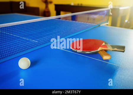 Zwei Schläger für Tischtennis oder Tischtennis und ein Ball auf einem blauen Tisch Stockfoto