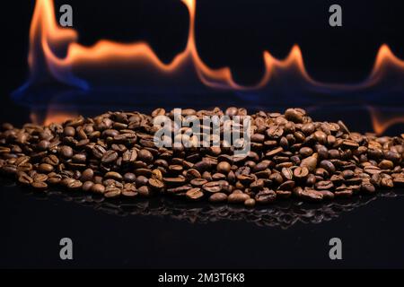 Brennender Kaffee auf schwarzem Hintergrund mit Reflexion. Aus der Nähe geröstete Kaffeebohnen Stockfoto