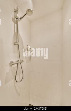 Eine Dusche in einem weiß gefliesten Badezimmer mit schwarzem Fliesenboden und an der Wand angebauten Wänden Stockfoto