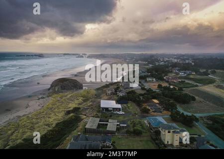 Sturmwolken bei Sonnenuntergang über Häusern an der Küste von Oregon. Stockfoto