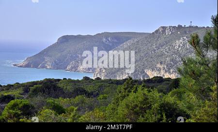 Die beeindruckenden felsigen Klippen bedeckt mit Grün an der Atlantikküste Portugals unter blauem Himmel Stockfoto