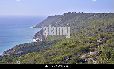 Die beeindruckenden felsigen Klippen bedeckt mit Grün an der Atlantikküste Portugals unter blauem Himmel Stockfoto