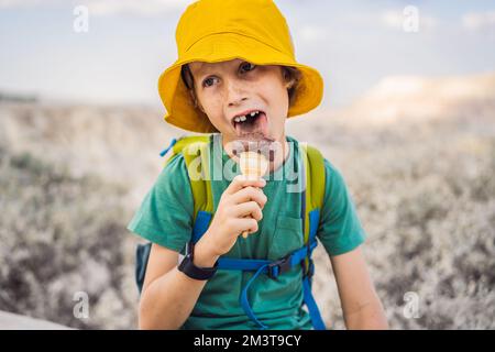 Tourismusjunge, der türkisches Eis isst, während er das Tal mit Felsformationen und Feenhöhlen in der Nähe von Goreme in Kappadokien, Türkei, erkundet Stockfoto