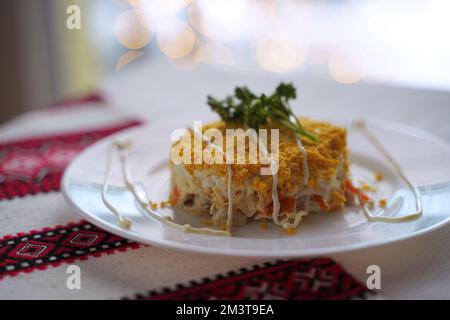 Hausgemachter Mimossalat. Traditionelle ukrainische Küche auf dem Tisch mit bestickter Tischdecke. Stockfoto