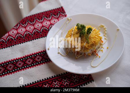 Hausgemachter Mimossalat. Traditionelle ukrainische Küche auf dem Tisch mit bestickter Tischdecke. Stockfoto