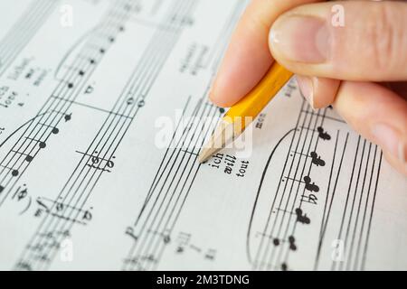 Lemberg, Ukraine - 13. Dezember 2022: Klaviermusik, Noten auf Papier. Die Hand macht Notizen mit einem Bleistift auf Papier. Blick von oben Stockfoto