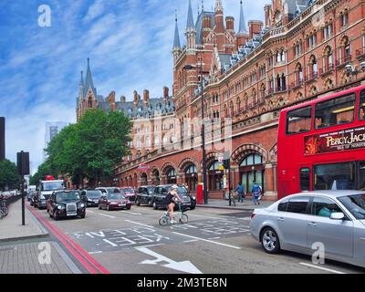 London, England - Stationen vor der historischen St. Bahnhof Pancras, während ein Radfahrer auf einem klappbaren Fahrrad die Straße überquert. Stockfoto