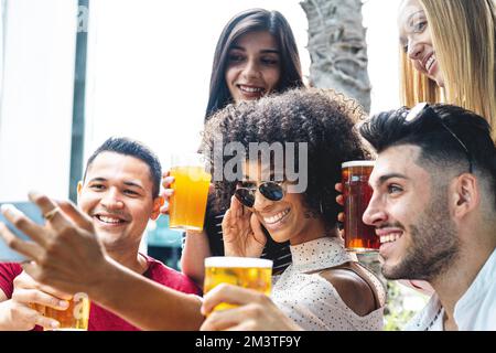 Multirassische Freunde, die ein Selfie in der Gruppe machen, die vor der Kamera lächelt, junge Leute im Freien lacht und lustige, fröhliche Leute in der Kneipe hat Stockfoto
