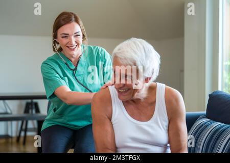 Junge Pflegekraft hilft Senioren zu Hause und überprüft Vitalparameter, Krankenschwester hilft ihrem alten Patienten im Pflegeheim, freundliches Pflegeheim l Stockfoto