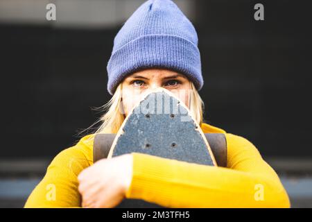 Intensiver Gesichtsausdruck einer jungen Frau, die Skateboarden, Z-Generation und Lebensstil der Jugend nutzt Stockfoto