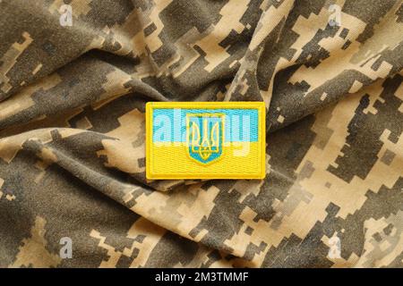 Pixeliges digitales Tarnmaterial mit ukrainischer Flagge und Wappen auf Chevron in Blau und Gelb. Attribute der ukrainischen Soldatenuniform Stockfoto