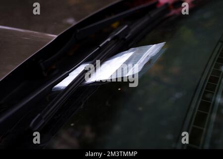 Parkschein in einer Plastiktüte mit Reißverschluss unter Autowischer an der Windschutzscheibe Stockfoto