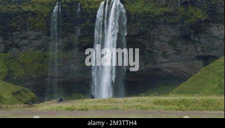 Der wunderschöne Wasserfall Seljalandsfoss Island aus der Ferne mit unbekannten Touristen, die herumlaufen Stockfoto