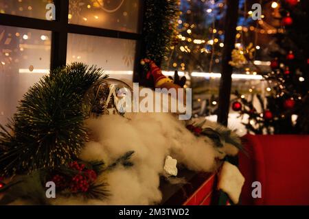 Festliche Weihnachtsdekoration des Kamins im Innenraum. Künstlicher Schnee mit Fichtenzweigen, rote Heilige, ein Schneeball am frostigen Panorama Stockfoto