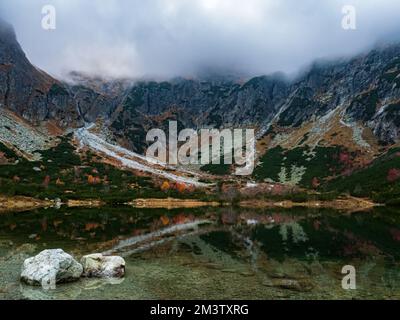 Felsen und Reflexionen in einem Bergsee, Herbstfarben wunderschönes Laub bewölkt Wetter Slowakei, Tatra Berge Stockfoto