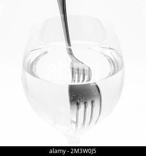 Vista de un tenedor distorsionado dentro de una vaso lleno de agua, demostrando la refracción de la luz Stockfoto