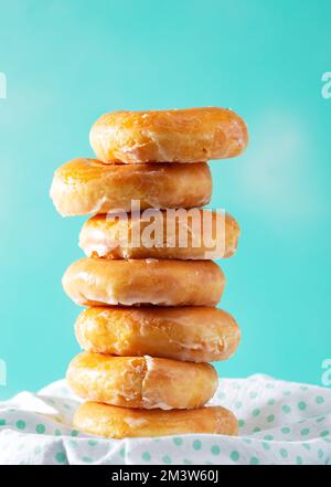 Stapel glasierter Donuts auf einem aquafarbenen Hintergrund mit Kopierbereich Stockfoto