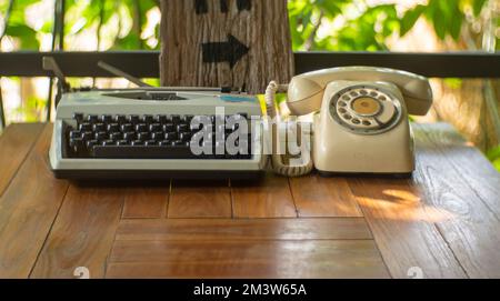 Eine Schreibmaschine und ein altes Telefon auf einem Holztisch Stockfoto