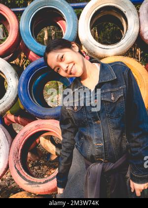 Die Frau trug ein Jeansshirt vor dem Hintergrund bunter Reifen. Stockfoto