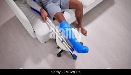 Junger Mann Mit Gebrochenem Bein, Der Auf Dem Sofa Sitzt Stockfoto