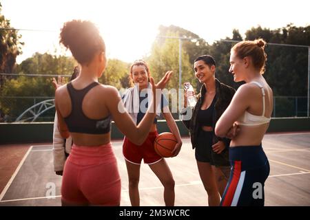 Vorschläge, wie wir gewinnen können. Eine vielfältige Gruppe von Freunden bereitet sich auf ein gemeinsames Basketballspiel während des Tages vor. Stockfoto