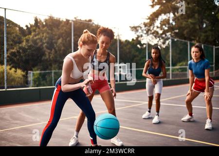 Das ist ein Wettkampfsport. Eine vielfältige Gruppe von Sportlerinnen, die tagsüber gemeinsam ein Wettkampfspiel mit Basketball spielen. Stockfoto
