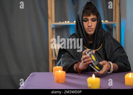 Der Mann der Pythonin liest Tarot-Karten auf einem Tisch mit Kerzen. Speicherplatz kopieren Stockfoto