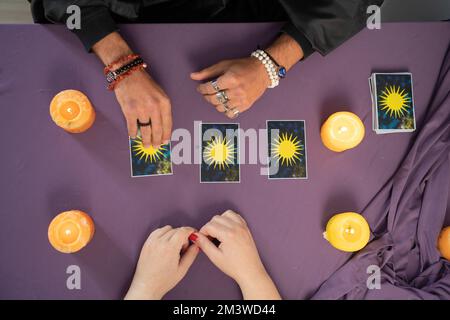 Ein Wahrsager, der Tarotkarten in der Hand hält, und eine nicht wiedererkennbare Frau, die die Karte auswählt Stockfoto